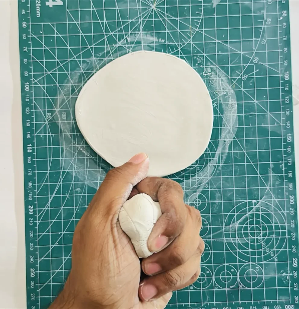 kneading a fresh piece of clay to make the tray rim
